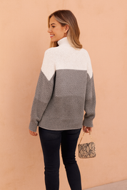 Stylish women’s tricolor knit sweater in white, light gray, and charcoal gray with a high turtleneck, paired with fitted black jeans and ankle boots.