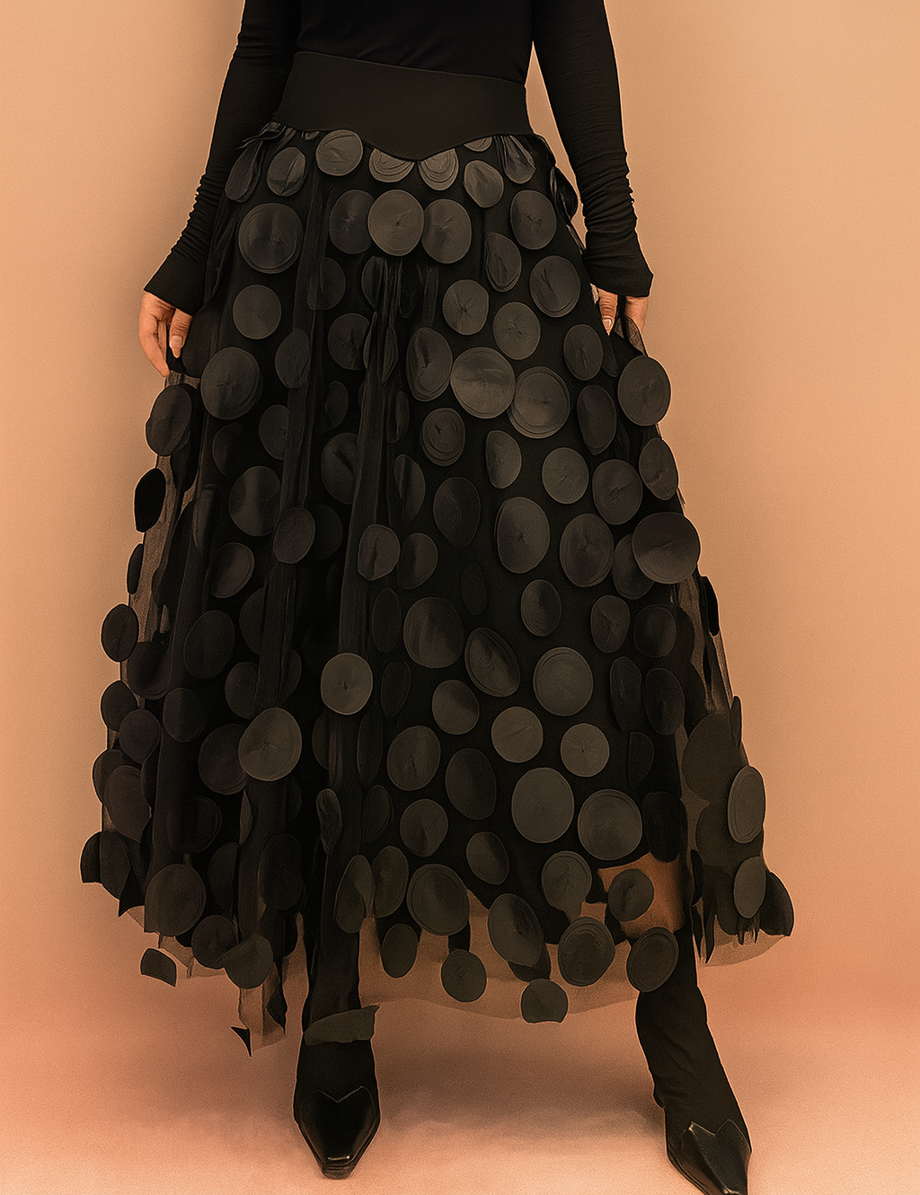 Laura – Elegant black summer skirt featuring large circular appliqués, styled with a fitted black top and boots, perfect for bold fashion statements in a chic editorial setting.