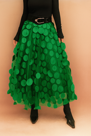 Laura – Elegant light green summer skirt featuring large circular appliqués, styled with a fitted black top and boots, perfect for bold fashion statements in a chic editorial setting.