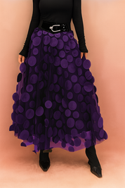 Laura – Elegant violet summer skirt featuring large circular appliqués, styled with a fitted black top and boots, perfect for bold fashion statements in a chic editorial setting.