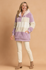  Color-block faux fur zip-up hoodie in lavender, cream, and beige with drawstring hood, paired with cream slim-fit pants and tan suede ankle boots.