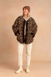 Leopard print button-up jacket with dark brown trim, paired with beige pants and cream lace-up boots.