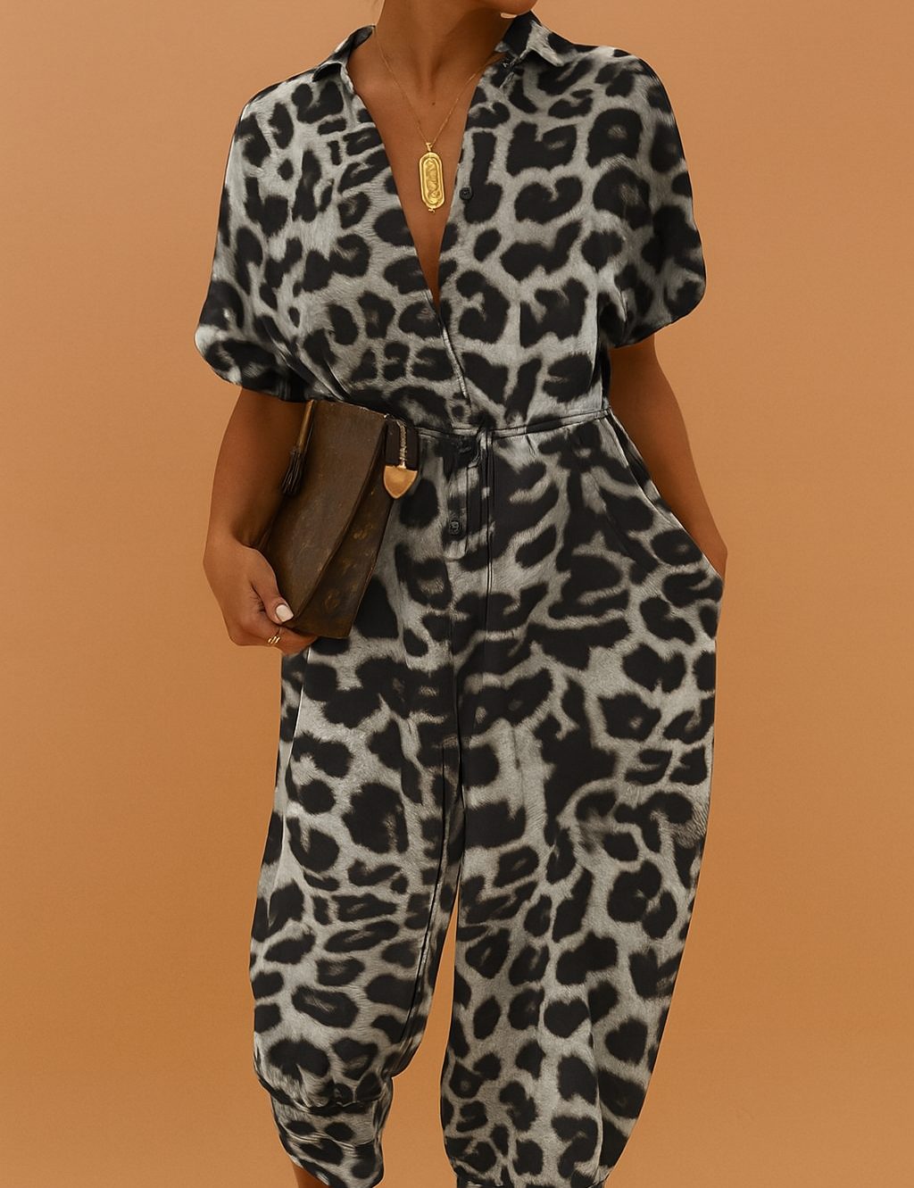 Leopard print jumpsuit with short puffed sleeves, a deep V-neckline, elastic cinched waist, and full-length tapered pants in black and gray tones.