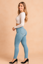 High-waisted light blue skinny jeans paired with a fitted long sleeve white crop top, showcasing precise stitching, smooth stretch denim texture, and a seamless body-contouring cut