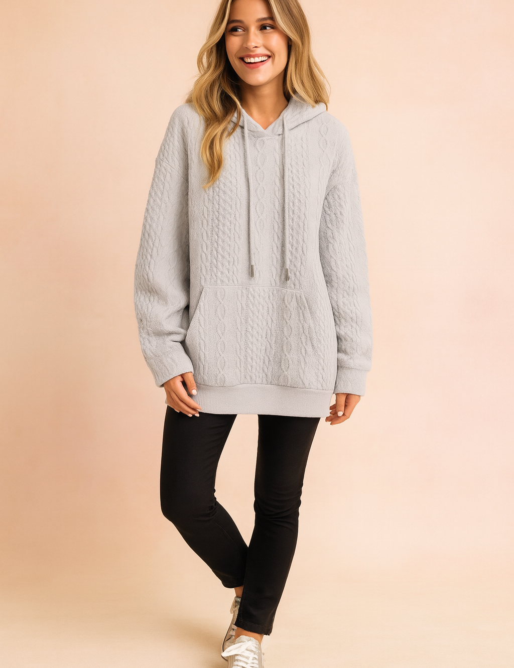 Light gray cable knit hoodie with a front pocket, drawstring hood, and textured knit pattern, paired with slim black pants and casual sneakers