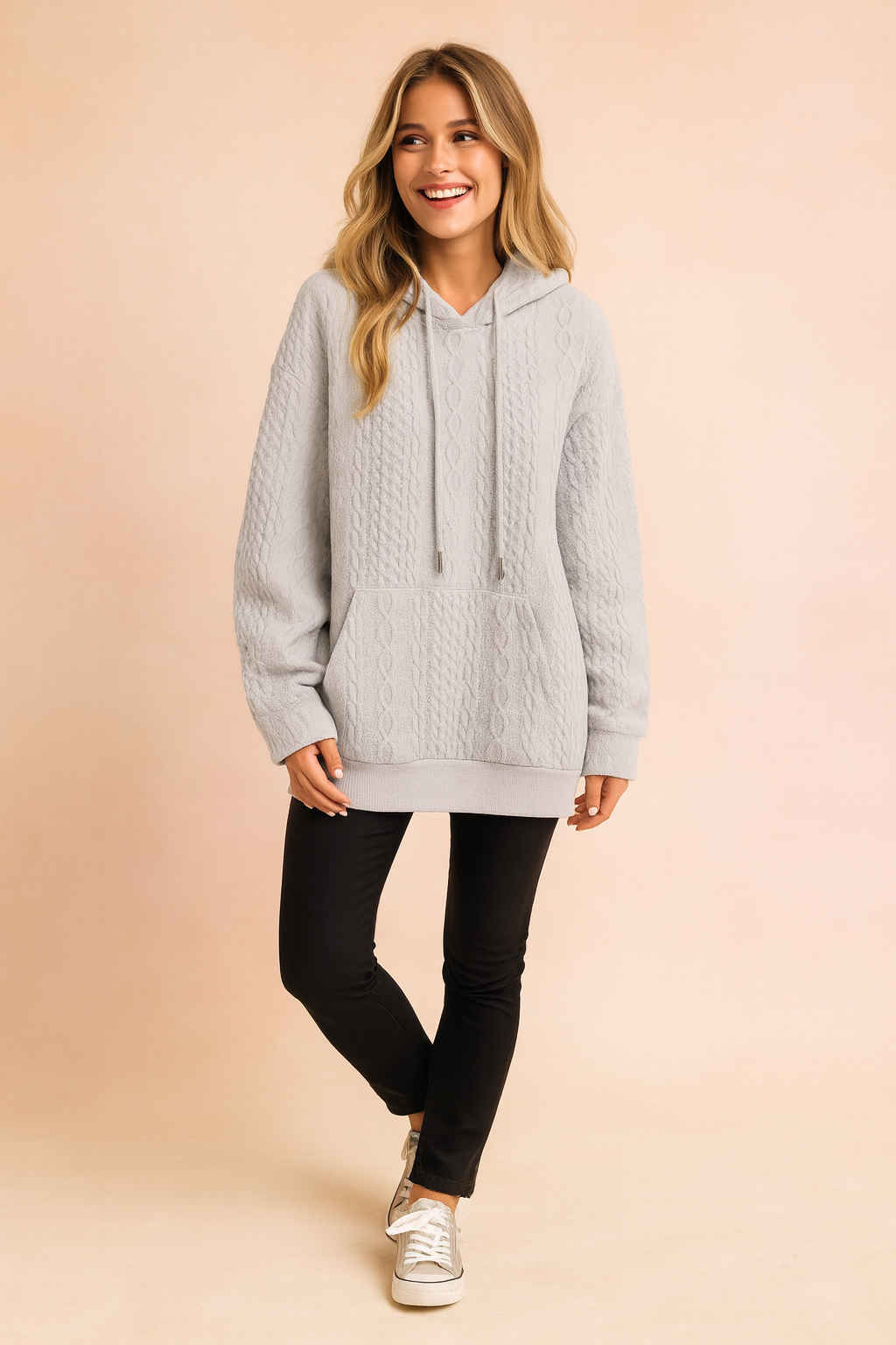 Light gray cable knit hoodie with a front pocket, drawstring hood, and textured knit pattern, paired with slim black pants and casual sneakers
