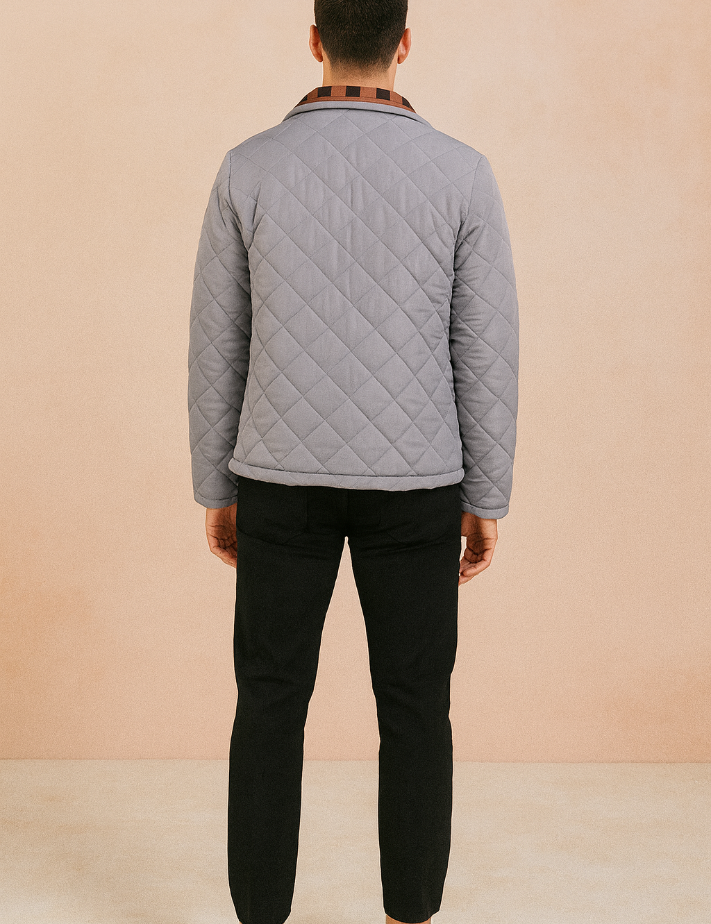 Back view of a light gray diamond-quilted jacket with a straight hem and structured collar, paired with black trousers and white sneakers.
