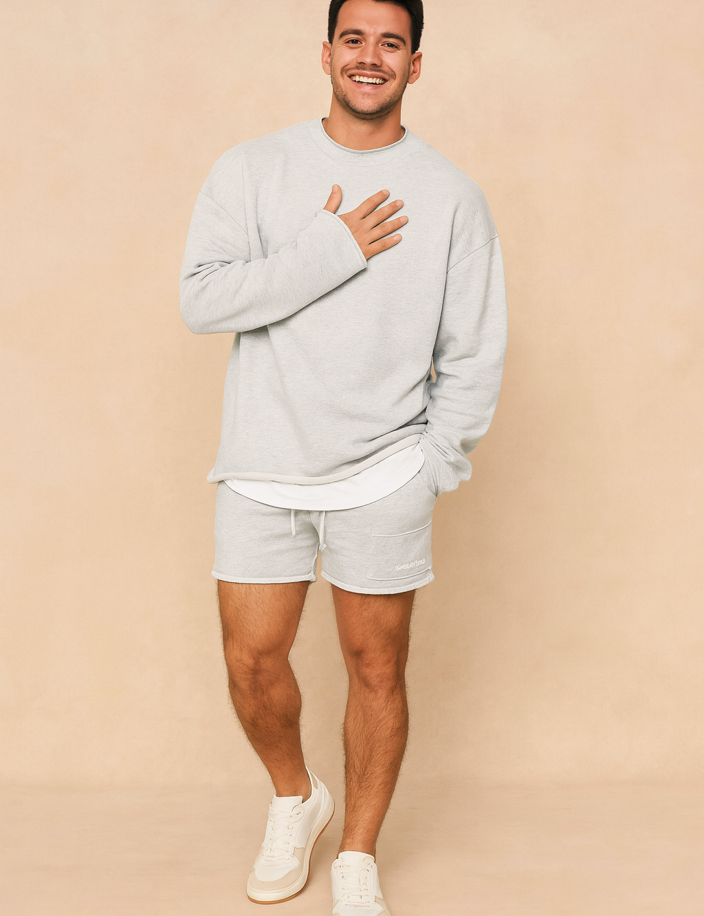 Light grey casual men’s lounge set featuring a relaxed-fit long-sleeve sweatshirt with layered hem detail and matching drawstring shorts for a minimalist streetwear look.