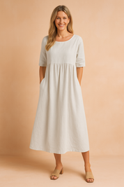 Elegant light grey midi dress with half sleeves, side pockets, and a gathered waistline, crafted in a soft, breathable fabric for a relaxed and polished silhouette.