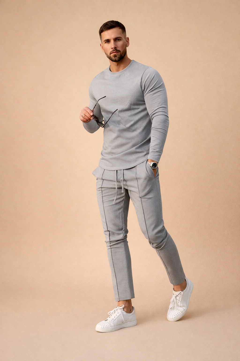 Light grey slim-fit long-sleeve shirt paired with matching tailored jogger trousers featuring subtle seam piping, worn with clean white low-top sneakers in a modern minimalist men’s outfit.