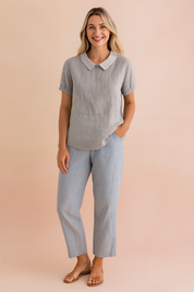 Light gray short-sleeve linen blouse with a white Peter Pan collar and gathered cuffs, paired with straight-cut light blue linen trousers and tan open-toe flats.