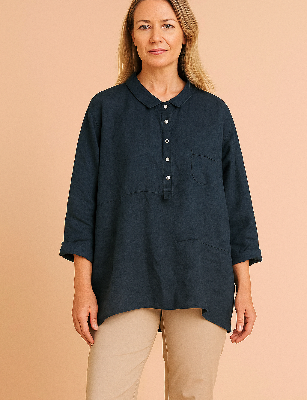 Navy blue linen women's shirt with collar and buttons, modeled by a European woman with long ash blond hair, fashion photography on a soft sand pink background.