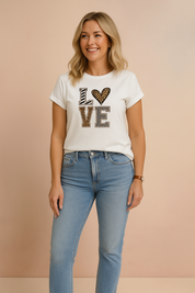 White graphic t-shirt with "LOVE" print in mixed animal and geometric patterns, styled with light-wash high-rise jeans.
