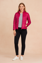 Magenta quilted puffer jacket with horizontal stitching, high collar, and zip closure, paired with slim black pants and a striped inner top.