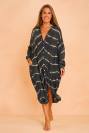 Confident European woman in a loose black and beige tie-dye maxi shirt dress with buttons.