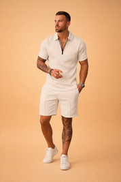 Luxury men’s summer two-piece outfit featuring a light grey short-sleeve polo shirt and matching tailored shorts, crafted from textured jacquard fabric with a refined geometric pattern, zip-neck polo collar, clean hem finishes, and a coordinated all-over print with consistent color tone and fabric structure.