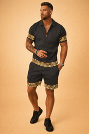 Luxury black short-sleeve polo shirt and matching tailored shorts set featuring an all-over subtle geometric woven pattern, refined zip collar detail, and contrasting gold Greek key trim on sleeves, hem, and shorts cuffs, finished in a coordinated premium summer two-piece ensemble.