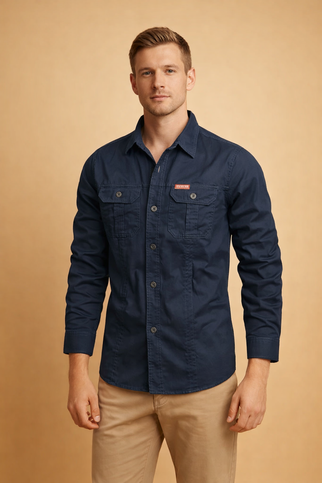Long-sleeve navy button-down shirt with structured collar, front button closure, dual flap chest pockets, reinforced seams, and tailored fit, paired with straight-cut beige chinos for a clean, modern menswear look.