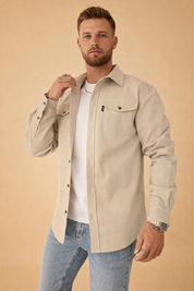 Men’s structured overshirt layered over a fitted crew-neck top, styled with straight-cut denim jeans, featuring a clean button-front design, chest flap pockets, and a tailored yet relaxed silhouette suitable for smart-casual wear.