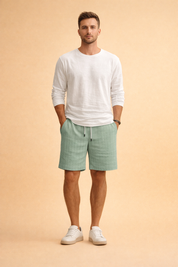 Mint green ribbed drawstring summer shorts paired with a clean white long-sleeve casual top and minimalist white low-profile sneakers, creating a relaxed yet refined warm-weather outfit with a lightweight textured finish and balanced proportions.
