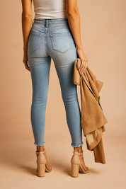 High-waisted ombré skinny jeans with light wash, subtle back pocket fading, and frayed hems, styled with nude block-heeled sandals and a beige trench coat.