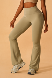 High-waisted beige flared workout pants with clean contour stitching and a smooth stretch-fit fabric, styled with chunky neutral sneakers for an athletic, modern look.