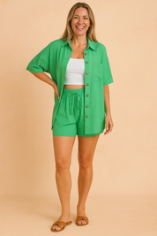 Two-piece women's casual coords set featuring a button-up short-sleeve shirt with front pocket and drawstring high-waisted shorts, all in solid bright green with matching buttons and smooth lightweight texture.