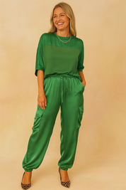 Relaxed-fit satin co-ord set in emerald green, featuring a half-sleeve top and drawstring jogger-style cargo pants with flap pockets, styled with leopard-print pointed heels.