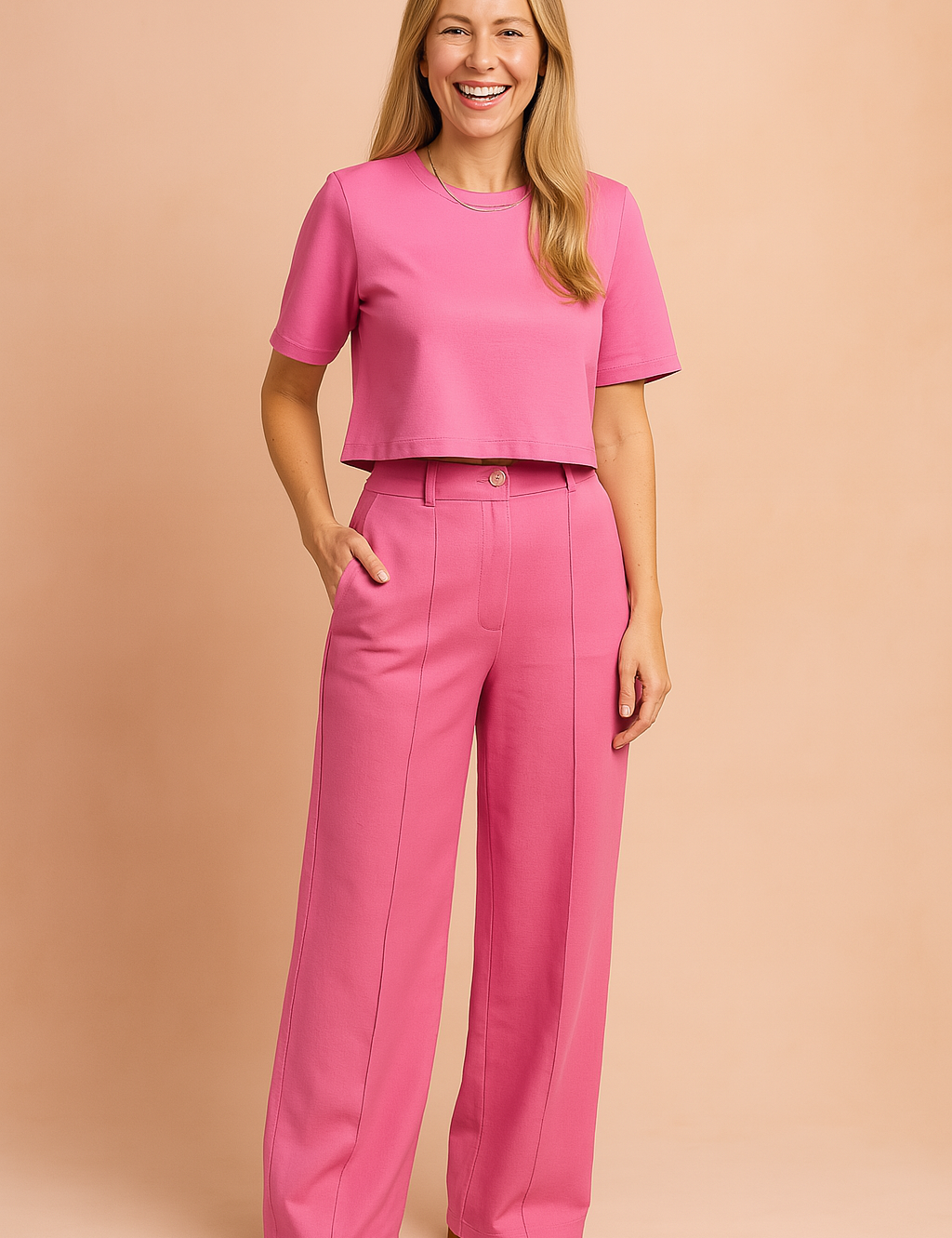 Two-piece women's coord set featuring a short-sleeve crop top and high-waisted wide-leg trousers in a solid fuchsia tone, styled with a central crease line and button-closure waistband for a sleek, modern silhouette.