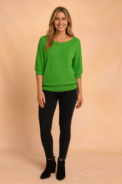Bright green knit sweater with three-quarter sleeves and ribbed cuffs, styled with black skinny jeans and suede ankle boots.