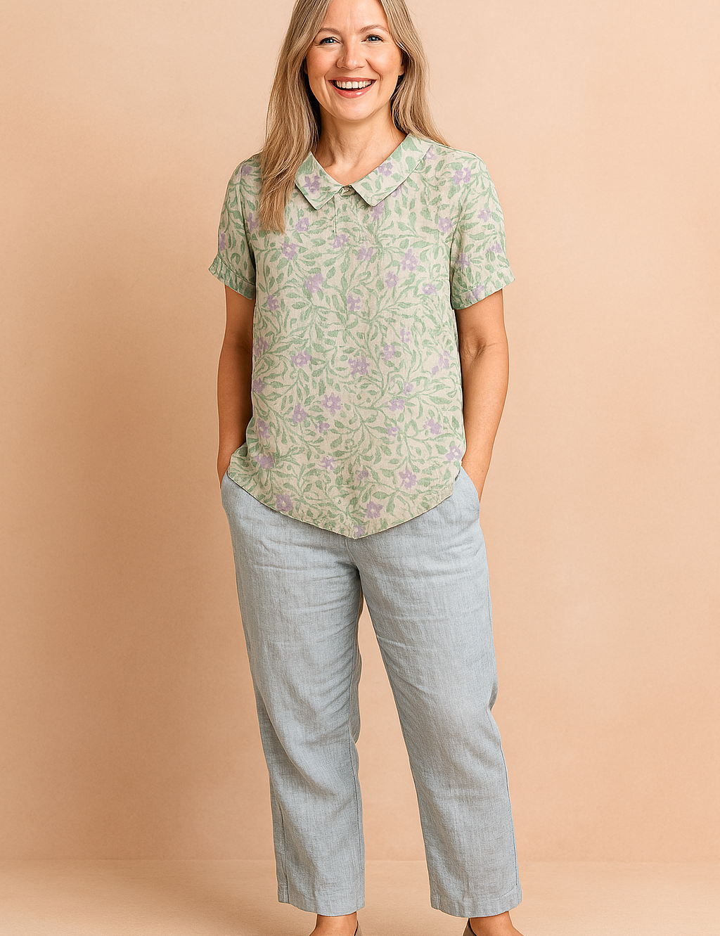 Short-sleeve button-up blouse with a rounded collar, featuring a light green leafy vine pattern and delicate lavender floral print on a light beige base.