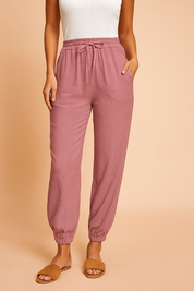 High-waisted mauve jogger pants with adjustable drawstring, subtle vertical texture, elastic ankle cuffs, and functional side pockets, styled for a relaxed casual look.