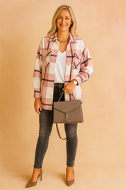 Oversized pink, cream, and black plaid shacket with white V-neck tee and faded charcoal skinny jeans, styled with taupe heels and a structured gray handbag.