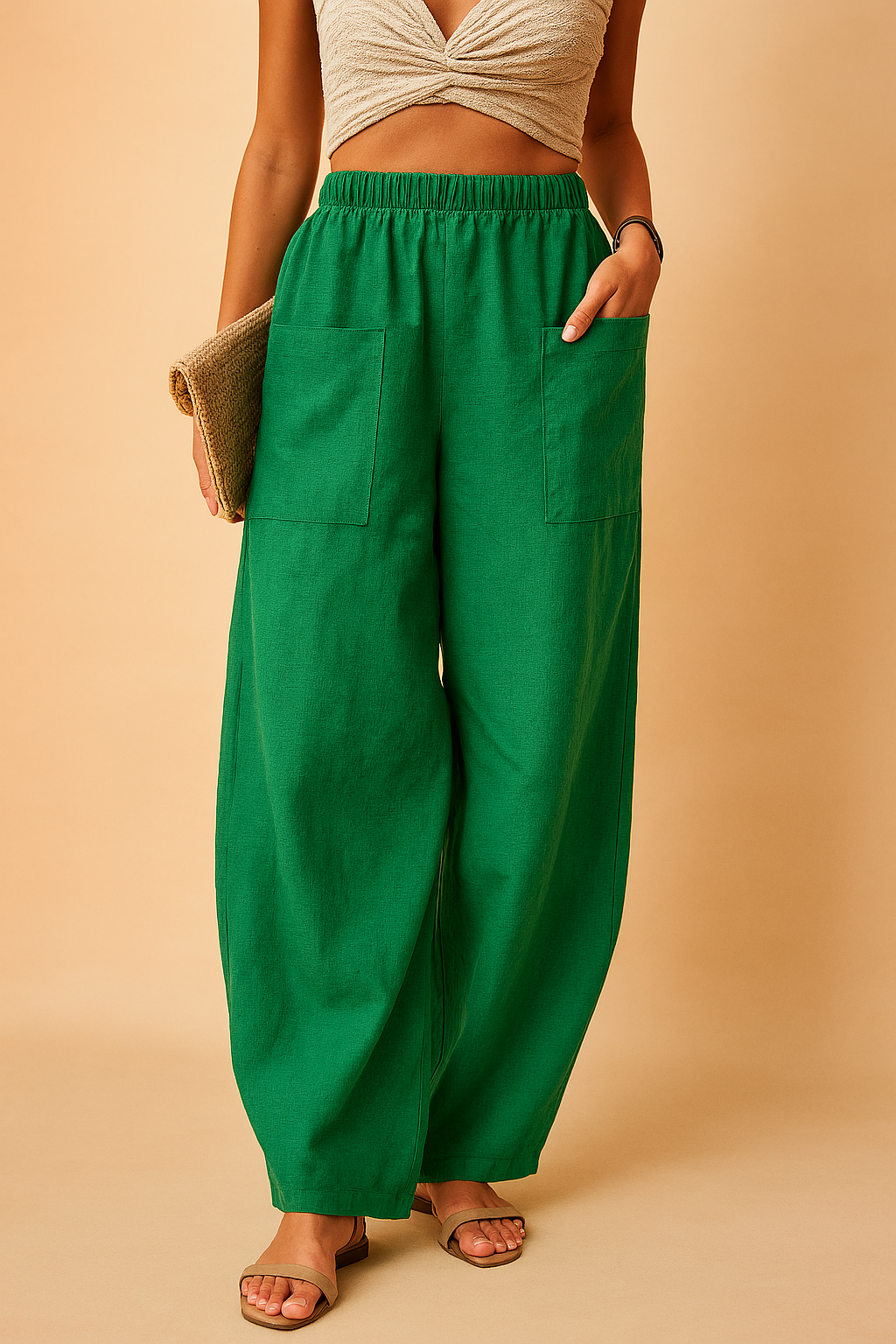 High-waisted wide-leg green linen pants with oversized front patch pockets, styled with flat beige sandals and a woven clutch for a relaxed summer look