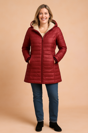 Mid-thigh length quilted puffer coat in rich deep red with horizontal stitching, a plush beige fleece lining, full-length front zipper, and matching red knit cuffs, styled with a hood and slightly flared hem for a flattering silhouette.