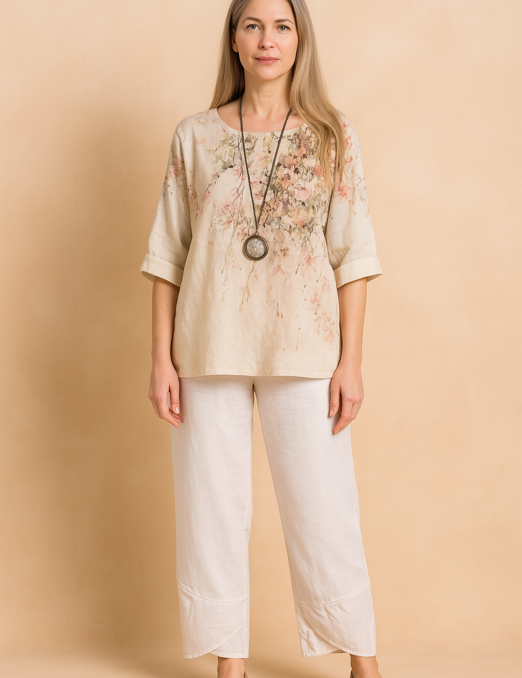 Two-piece linen blend summer outfit featuring a loose, elbow-sleeve cream top with a delicate pink and green floral print and round neckline, paired with white ankle-length pants with cross-panel hems and an elastic waistband.