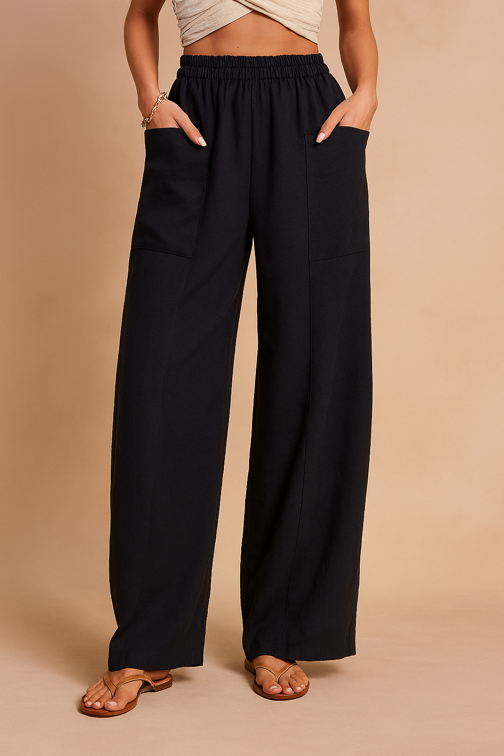 Wide-leg navy linen pants with elastic waistband and large front patch pockets, styled with tan sandals and a twisted crop top.