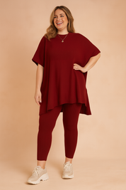 Ribbed knit two-piece loungewear set featuring an oversized short-sleeve tunic top and matching fitted leggings in red, styled with chunky cream sneakers.