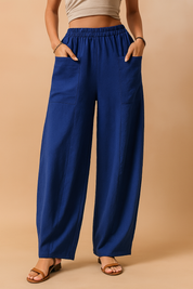 Wide-leg royal blue linen trousers with oversized front patch pockets and an elasticated high-rise waistband, styled with tan sandals for a relaxed yet polished look.