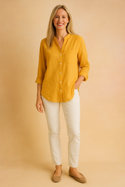 Mustard yellow linen shirt with a chest pocket and full button front, styled with slim white trousers and taupe ballet flats.