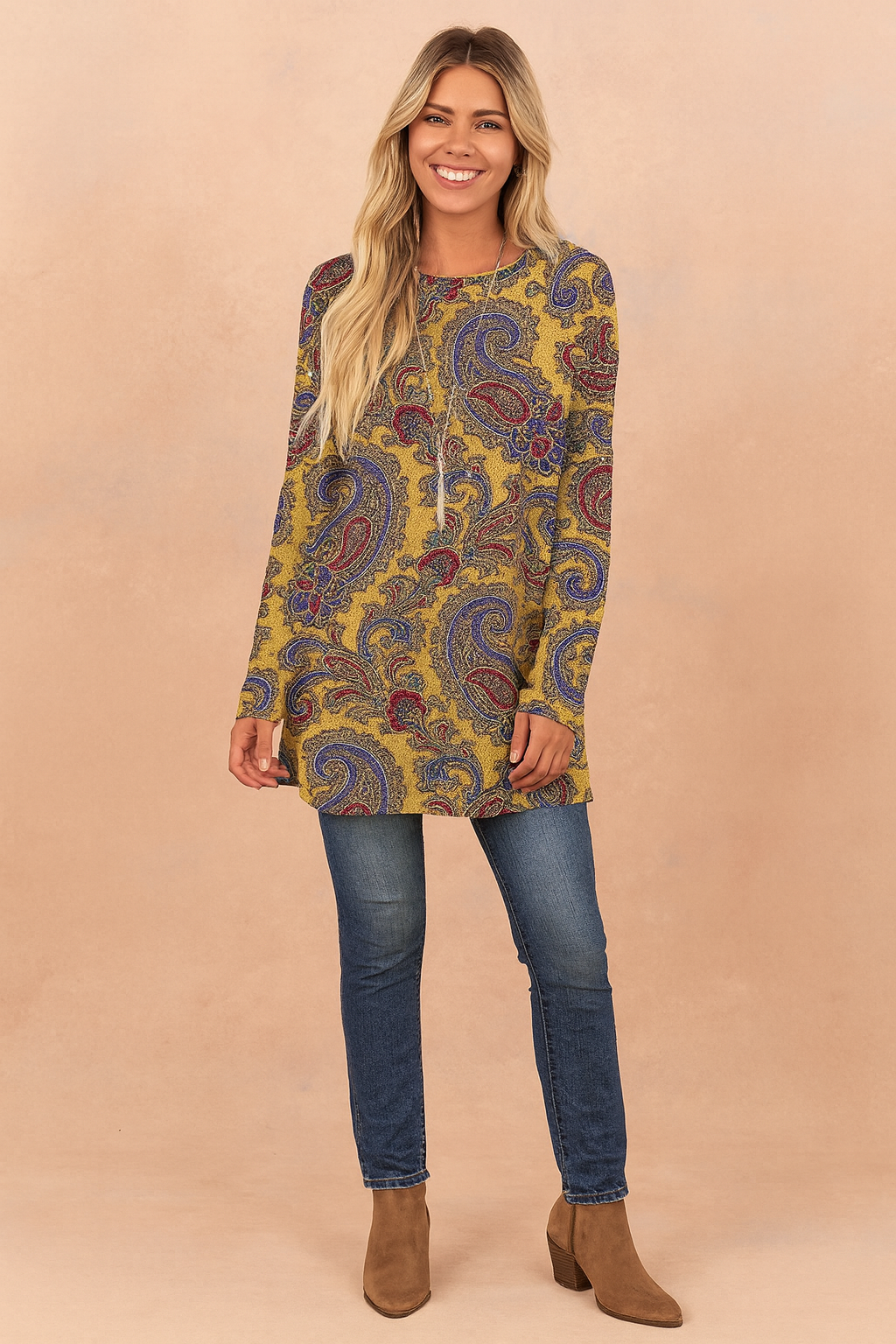 Mustard yellow paisley print long-sleeve tunic top with a relaxed fit, paired with dark blue skinny jeans and tan suede ankle boots.