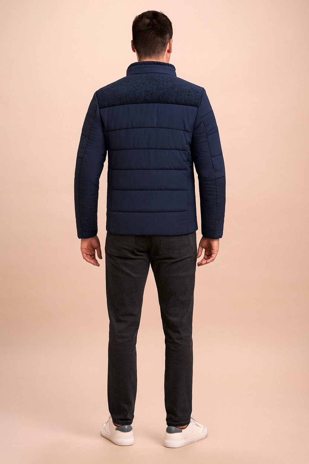 Back view of a navy blue padded jacket with textured shoulder panel, horizontal quilted stitching, and stand-up collar, styled for casual wear.