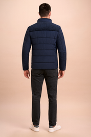 Back view of a navy blue padded jacket with textured shoulder panel, horizontal quilted stitching, and stand-up collar, styled for casual wear.