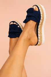 Women's navy blue espadrille platform sandals featuring oversized bow detailing on the upper and a braided jute midsole with a white chevron accent and thick white rubber outsole.