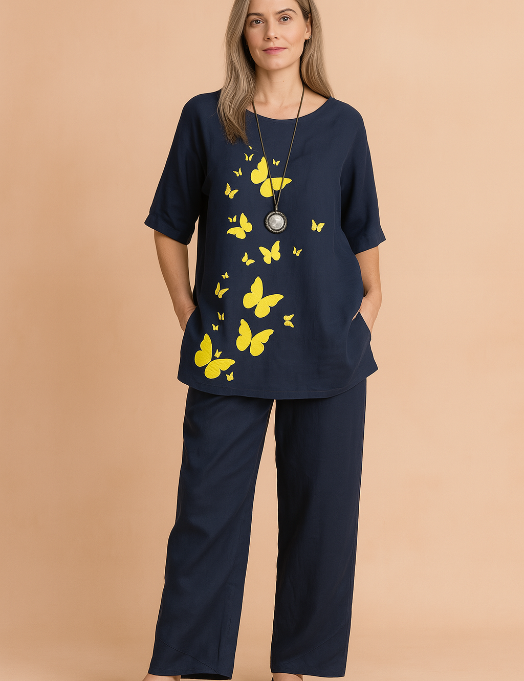 Two-piece navy blue cotton set featuring a half-sleeve top with bright yellow butterfly prints cascading down the front and matching wide-leg pants with minimal seam detailing.