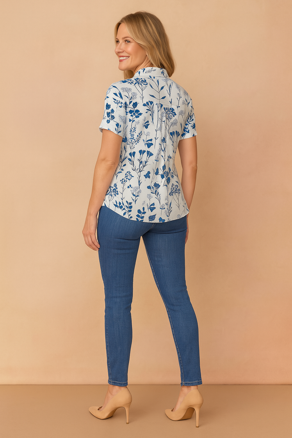 White short-sleeve blouse with navy botanical print, styled with slim-fit mid-wash denim jeans and beige heels.