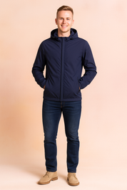 Navy blue hooded windbreaker jacket with front zipper and zippered side pockets, styled with slim dark denim jeans and beige suede shoes.