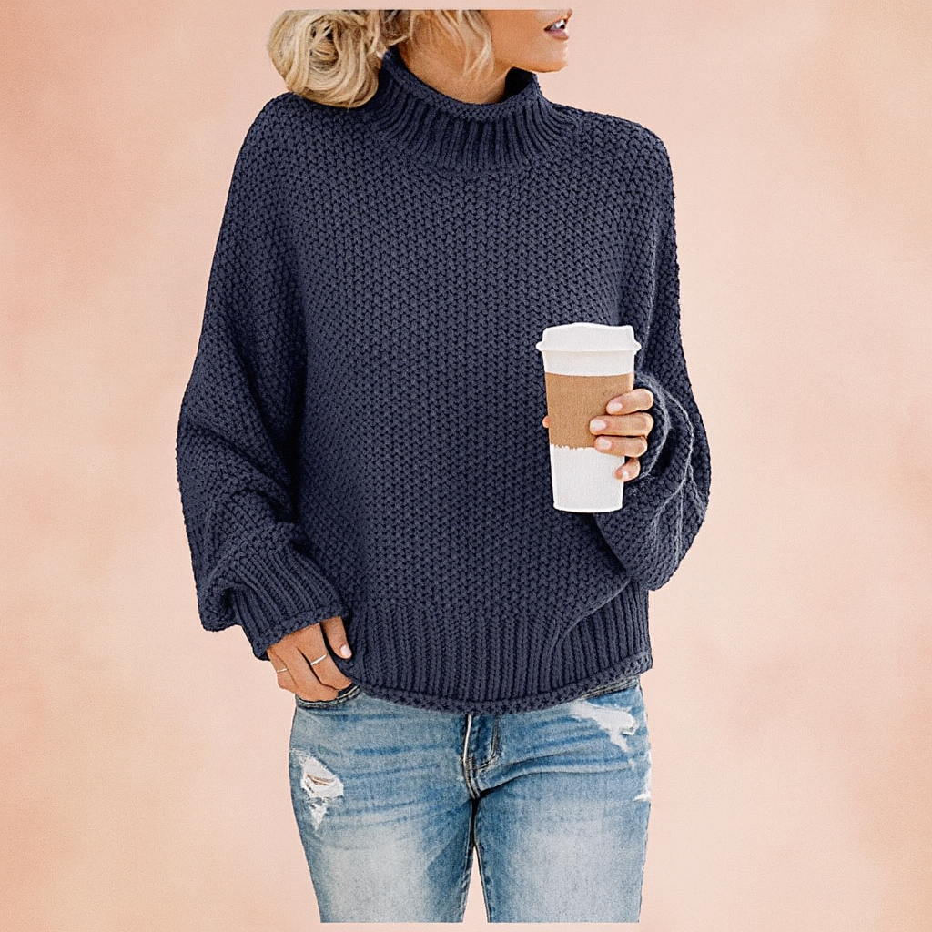 Navy chunky knit turtleneck sweater paired with distressed light blue jeans, styled casually with one hand in pocket and holding a coffee cup.