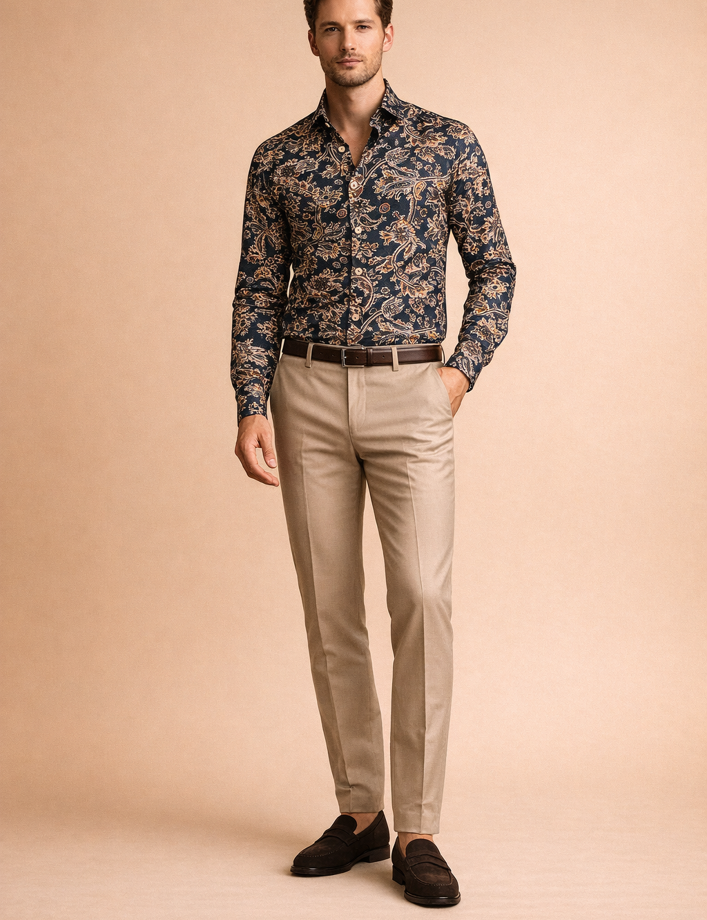 Slim-fit navy paisley button-up shirt with intricate floral motifs in beige, rust, and light blue, paired with tailored beige trousers and brown leather loafers