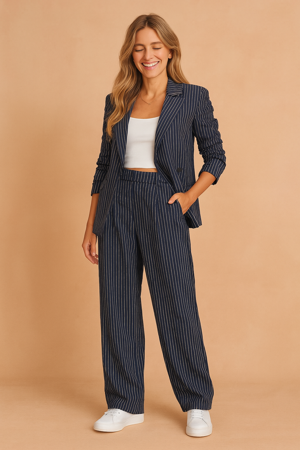 Navy blue pinstriped cropped blazer with matching wide-leg trousers, styled with a white fitted crop top and white sneakers for a modern business-casual look.